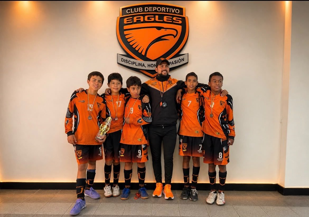 Jugadores del Club Deportivo Eagles celebrando con medallas y trofeo tras un torneo
