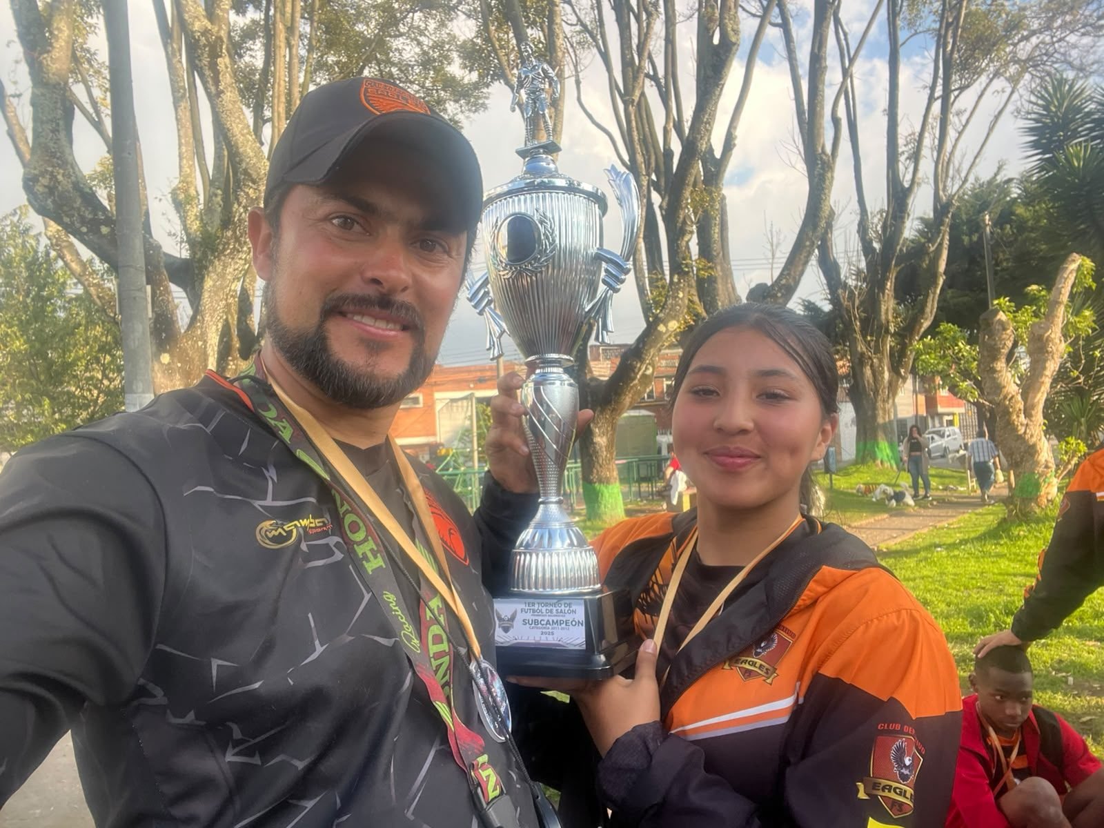 Entrenador y jugadora del Club Deportivo Eagles con trofeo de subcampeón